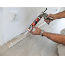 Application de colle de montage pour fixer une plinthe à un mur