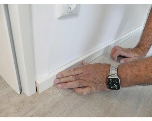 Pose d'une plinthe blanche contre un mur