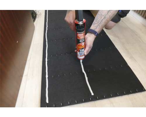 Application d'adhésif de montage sur un panneau isolant noir avec un applicateur