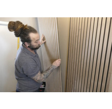 Un homme installe des panneaux acoustiques au mur pour l'absorption du son