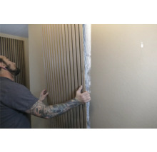 Un homme fixe des panneaux acoustiques au mur pour l'absorption du son et la décoration murale.