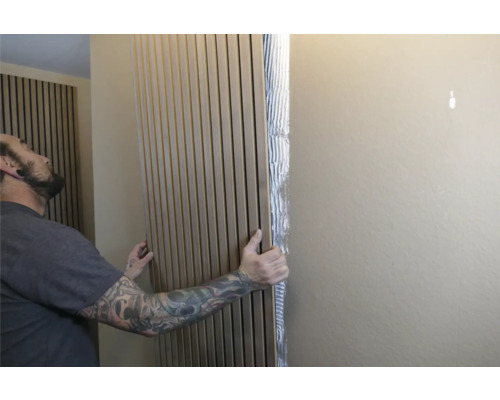 Un homme fixe des panneaux acoustiques au mur pour l'absorption du son et la décoration murale.