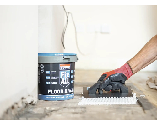 Un seau de colle Soudal Fix ALL et une personne appliquant de la colle avec une spatule.
