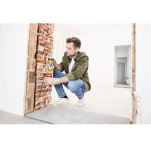 Mann trägt Bauschaum von Soudal auf eine Backsteinmauer auf.