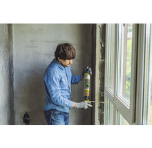 Mann dämmt Fenster mit Montageschaum