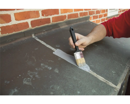 Une personne scelle des joints avec un pinceau.