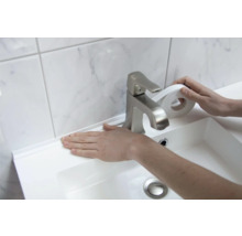 Application d'une bande d'étanchéité blanche sur un lavabo dans une salle de bains.