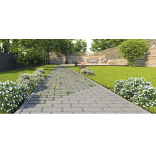 Vue de jardin avec pelouse, chemin de pierre et salon de jardin sur une terrasse en bois