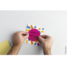 Une personne fabrique une carte d'anniversaire avec l'inscription Happy Birthday.