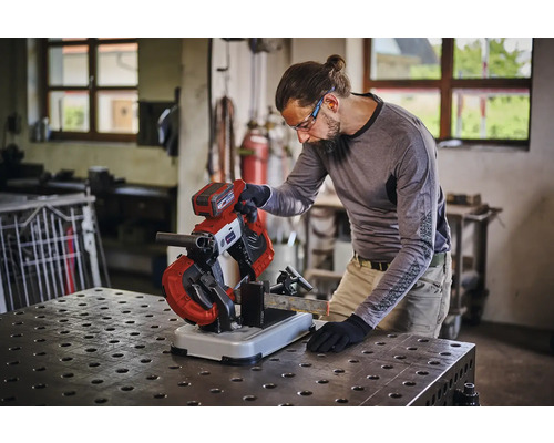 Mann bedient eine Metallsäge in einer Werkstatt.