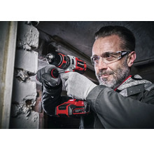 Un homme perce un mur avec une perceuse-visseuse sans fil Einhell.