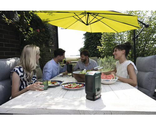 Gruppe von Personen beim Essen im Freien unter einem Sonnenschirm mit einem Bosch-Produkt auf dem Tisch.