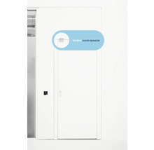 Capteur de porte Tedee monté sur le coin supérieur d'une porte blanche dans une pièce lumineuse.