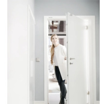 Une femme ouvre une porte d entrée d appartement blanche avec verrouillage multipoints dans une pièce moderne et lumineuse.