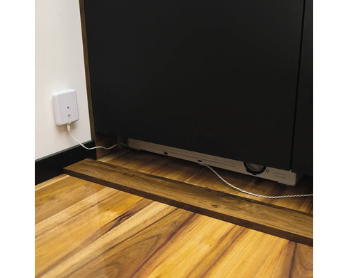 Vue détaillée d'un meuble bas avec prise et câble sur un plancher en bois