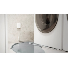 Détecteur d'eau en action à côté d'un lave-linge, eau sur le sol