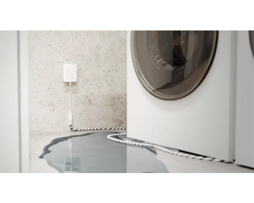 Détecteur d'eau en action à côté d'un lave-linge, eau sur le sol