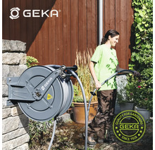 Scène de jardin avec tuyau d'arrosage GEKA enroulé et une femme arrosant des plantes, logo GEKA
