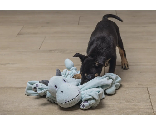 Un chiot joue avec une peluche sur le sol.