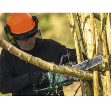 Homme avec casque de protection et tronçonneuse Bosch coupant un arbre
