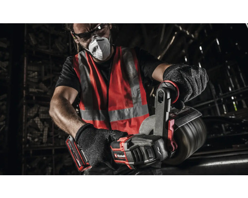 Ein Mann mit Schutzbrille, Atemschutzmaske, Warnweste und Handschuhen arbeitet mit einer Einhell Akku-Blechschere an einem Metallrohr.