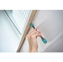 Main utilisant un outil de nettoyage sur un cadre de porte