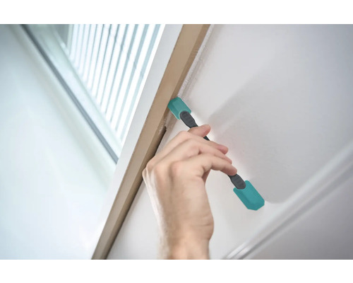 Main utilisant un outil de nettoyage sur un cadre de porte