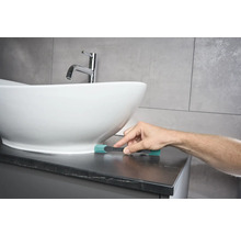 Scène d'une salle de bains avec un lavabo et une personne utilisant une brosse de nettoyage