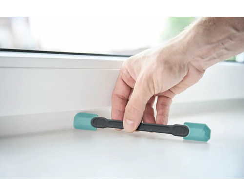 Une personne utilise une cale de fenêtre pour ouvrir une fenêtre.