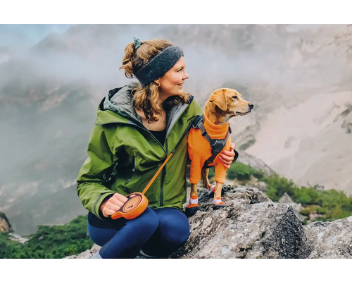 Femme avec chien en tenue de randonnée sur un rocher
