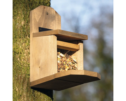 Vogelhaus aus Holz mit Futter gefüllt an einem Baum befestigt
