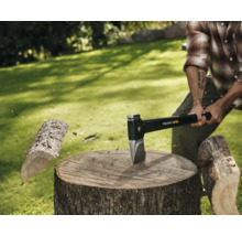 Homme fendant du bois avec une hache Fiskars sur une souche d'arbre à l'extérieur