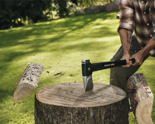 Homme fendant du bois avec une hache Fiskars sur une souche d'arbre à l'extérieur