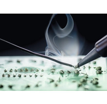 Fer à souder en train de souder sur une carte de circuit imprimé avec dégagement de fumée