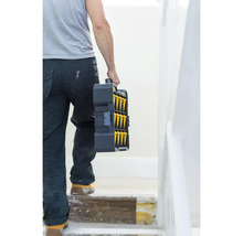 Une personne porte une boîte à outils dans un escalier.