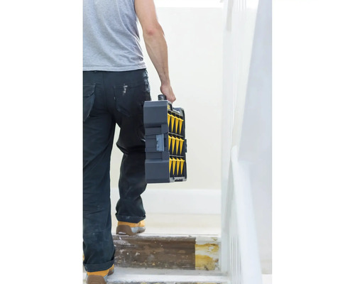 Une personne porte une boîte à outils dans un escalier.
