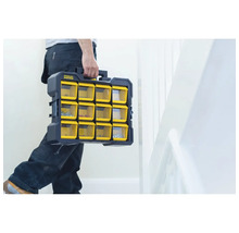 Un artisan transporte une boîte de rangement Stanley Fatmax avec des compartiments jaunes transparents.