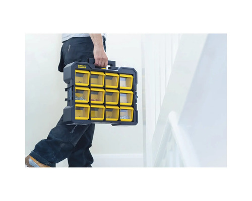Un artisan transporte une boîte de rangement Stanley Fatmax avec des compartiments jaunes transparents.