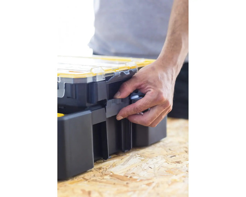 Une main ouvre une boîte à outils sur une table en bois