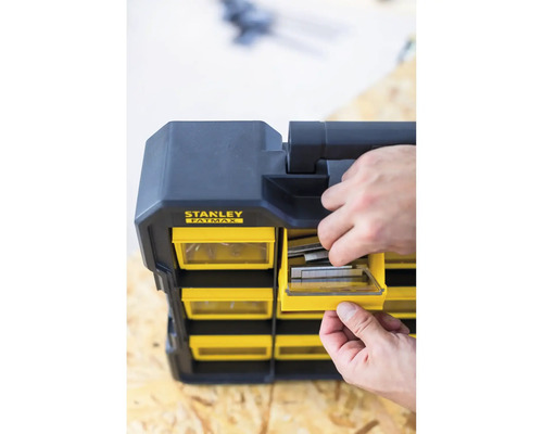Boîte de rangement Stanley Fatmax avec une main plaçant des agrafes dans un compartiment.