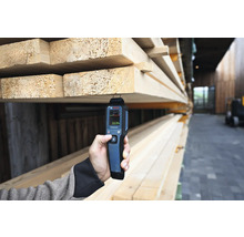 Eine Person misst die Holzfeuchtigkeit mit einem Feuchtigkeitsmesser von Bosch.