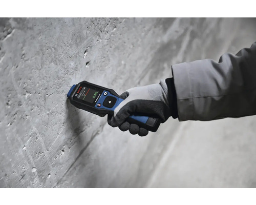 Main avec humidimètre Bosch sur un mur en béton