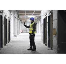 Bauarbeiter mit Schutzhelm und Warnweste bei der Arbeit auf einer Baustelle
