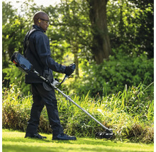 Homme coupant l'herbe avec un coupe-bordures sans fil dans le jardin.