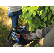 Gros plan d'une personne travaillant avec un taille-haie, mettant l'accent sur le fonctionnement et l'équipement de sécurité.