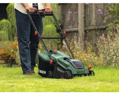 Eine Person bedient einen Rasenmäher auf einer Rasenfläche.