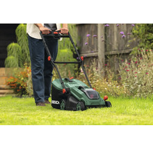 Une personne utilise une tondeuse à gazon dans le jardin.