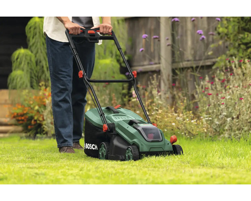 Une personne utilise une tondeuse à gazon dans le jardin.