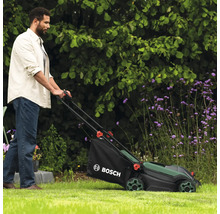 Un homme utilise une tondeuse à gazon Bosch dans le jardin.