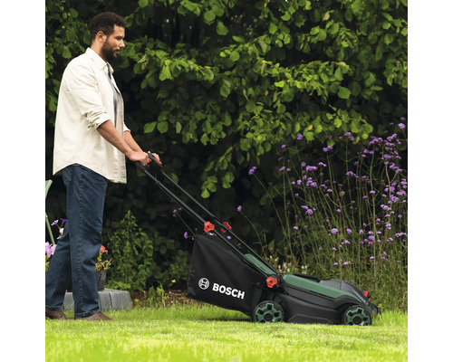 Un homme utilise une tondeuse à gazon Bosch dans le jardin.